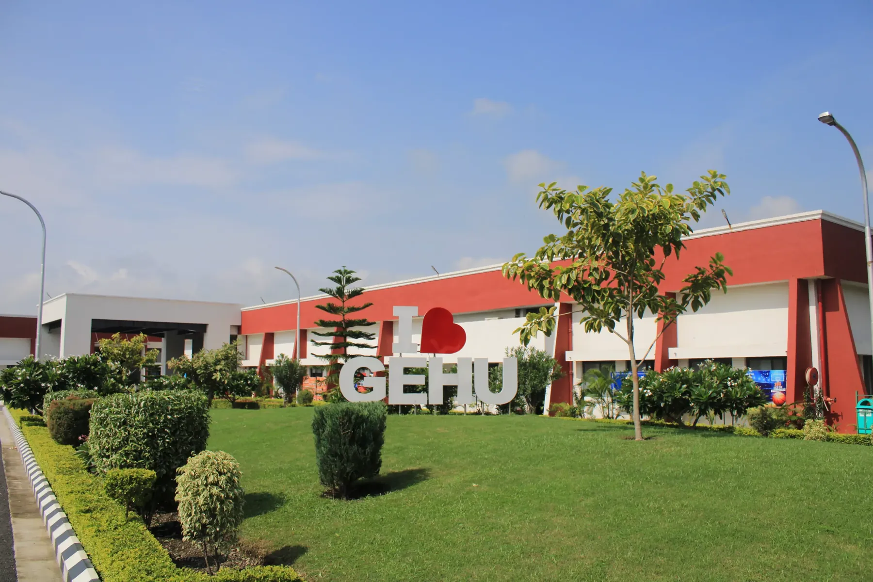 The lawns and red and white blocks of the Haldwani campus, with the GEHU sign