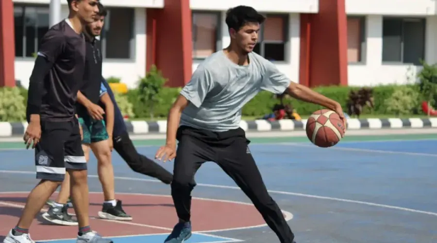 Students playing basketball on the court in front of the campus blocks