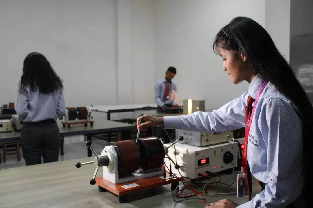 Students in uniform running an experiment at a bench in the campus physics lab